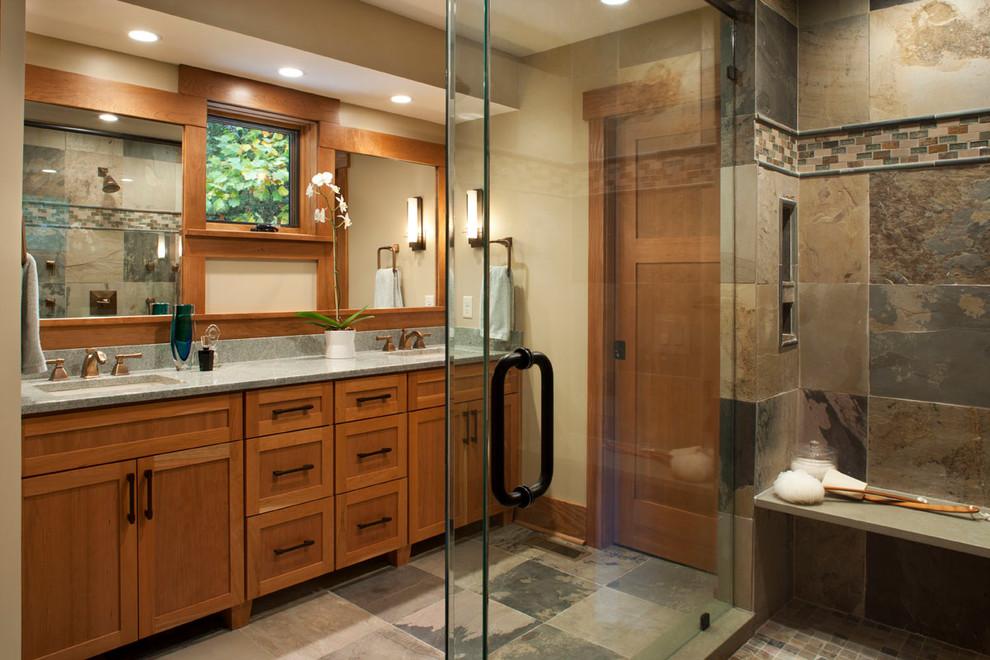 Warm Idaho bathroom with natural wood vanity, stone finishes and glass shower
